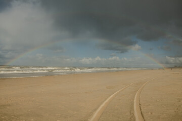plage avec traces de pneus et arc-en-ciel 