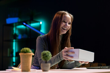 Happy gen Z girl excited to film unboxing video of various electronics, presenting features to...