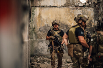 Air soft teammates in military uniforms with weapon on a mission in ruins