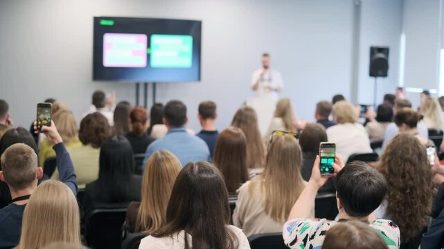 Diverse audience attentively listening to a speaker presenting at a business seminar in a conference room. Shows engagement, focus, and professional environment. - Powered by Adobe