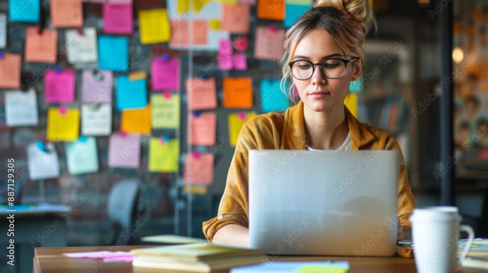 Aufkleber a woman sits at a desk in an office, focusing on her laptop while a wall of colorful sticky notes se