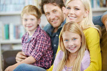 Parents, children and happy on sofa in portrait for love, care and relax for holiday, weekend or vacation at home. Family hug together with mom, dad and kids bonding on couch in living room or lounge