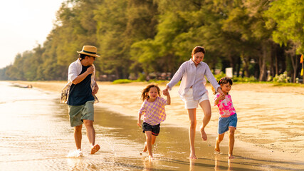 Happy Asian family enjoy and fun outdoor lifestyle travel at the sea on summer beach holiday vacation. Father, mother and child girl kids walking and playing together on tropical beach at sunset. © CandyRetriever 