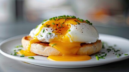 Toasted English muffin with poached egg and hollandaise sauce, close-up on white plate