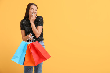 Beautiful young happy woman with shopping bags on yellow background