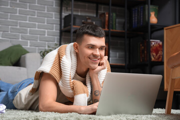 Male author using laptop on floor at home