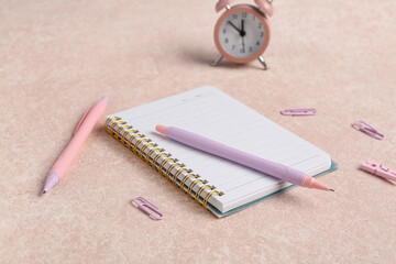 Pens with notebook and different school stationery on beige grunge background