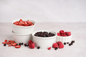 Bowls with tasty freeze-dried berries on light background