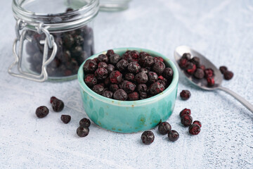 Bowl and glass jar with tasty freeze-dried black currant on light background