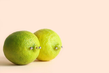 Fresh limes with nipple piercing on color background