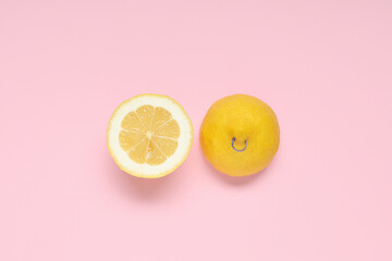 Halves of fresh lemon with nipple piercing on pink background