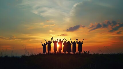 Silhouetted against a dramatic sunset, a group of graduates raise their arms in jubilation, celebrating their perseverance, hard work, and the dawn of a new chapter in their lives.