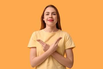 Obraz premium Young deaf mute woman using sign language on orange background