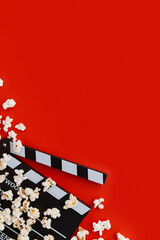 Popcorn and clapperboard on a red background. Flat lay, copy space