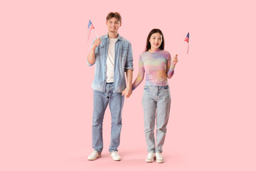 Fototapeta premium Young couple with flags of USA on pink background