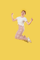 Young woman jumping on yellow background