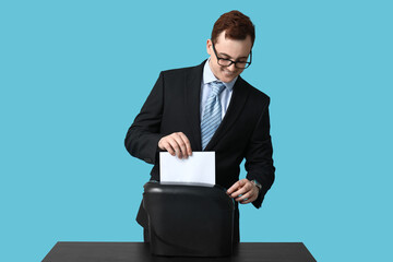 Young man destroying wrong document in shredder on blue background