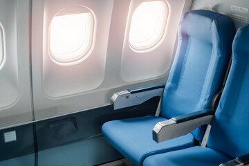 Close-up view of blue airplane seats with sunlight streaming through windows, showcasing modern aircraft interior design.