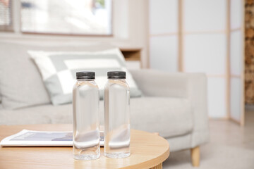 Bottles of water and magazine on table in living room, closeup