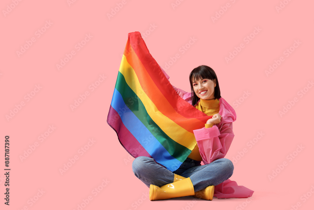 Wall mural beautiful young woman with lgbt flag sitting on pink background