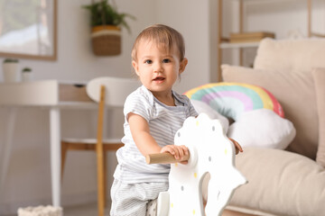 Cute little happy baby with rocking horse at home