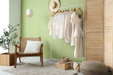Rack with white clothes near green wall in room