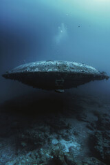 Flying saucer at the bottom of the ocean, dim blue underwater shot