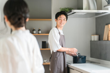 キッチンで料理・家事をする若いアジア人夫婦・カップル（自炊・共働き・ディンクス・趣味）  © buritora