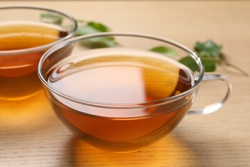 Refreshing green tea in cups on wooden table, closeup