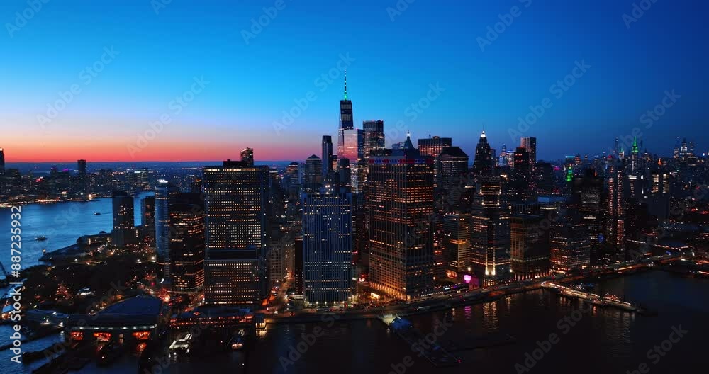 Wall mural Luminous skyline of Manhattan at dusk time. Drone footage from above the East River. Pink sky at horizon at backdrop.