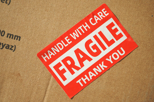 A cardboard box marked with a caution label for fragile goods handling during shipping