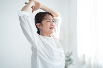 Fototapeta premium 部屋で伸びをする女性
