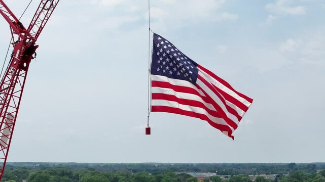Hung from a construction crane, the flag of the United States waves in the wind.