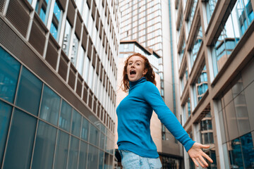 Excited Woman in Blue Sweater Walking Through City Street