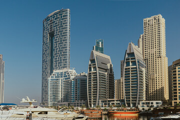 Obraz premium Skyline with marina water view, high-rise buildings, and traditional wooden boats on the waterfront line