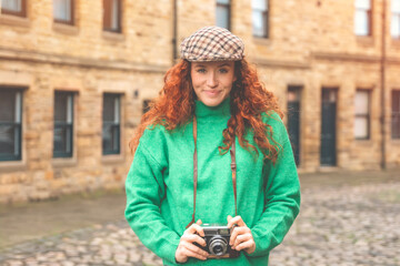 Young Woman With Camera Standing In Front Of Stone Buildings