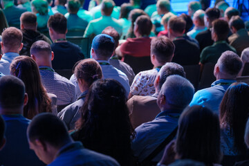 Audience is attentively listening to a speaker at a conference. Diverse group of people engaged in...