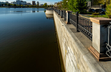 A concrete embankment of the river with a fence.