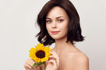 Beautiful young woman holding a sunflower on a white background