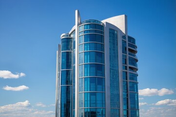Obraz premium Tall modern glass skyscraper with glass facade against blue sky