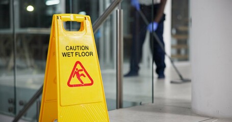 Caution, sign and cleaning for floor, janitor and hygiene service and dark at night in office. Mop, job and disinfection with equipment with warning and male person, disinfectant and wet ground