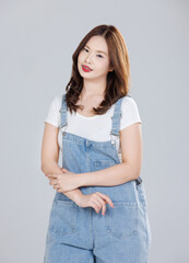 Portrait of Asian cute cheerful young girl wearing denim overalls, stylish model woman with happy and cool sweet smile standing posing isolated on white background, Teenage and youth fashion.