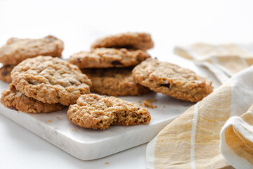 Close view of freshly baked oatmeal cranberry cookies on a marble board with a yellow kitchen towel on a side