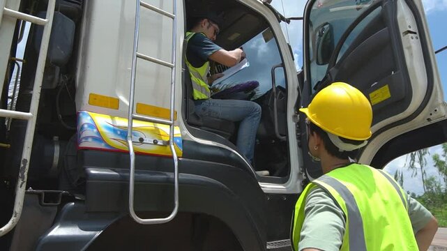 Male Asian truck driver signing documents Foreman with safety hats and safety vest standing by freight vehicle.