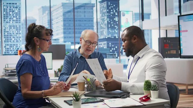 Mature couple receiving expert financial advice on retirement planning, focusing on maximizing savings and long term financial security. Counseling on life insurance and funds from planner. Camera B.