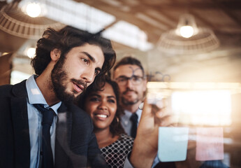 Obraz premium Businessman, coaching and writing in meeting with glass board for schedule planning or brainstorming at office. Man training staff, team or employees for mind map, strategy or tasks at workplace