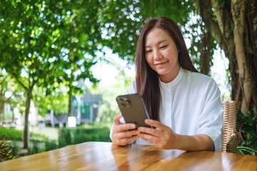 Portrait image of a young woman holding and using mobile phone in the outdoors