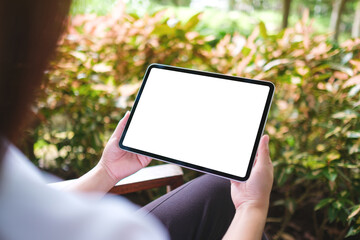 Mockup image of a woman holding digital tablet with blank white desktop screen in the outdoors