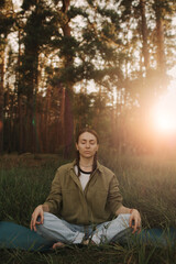 Unity with nature and wellness concept. Overjoyed woman enjoying with a yoga mat for yoga practice meditates in the park. Concept of female people and healthy natural lifestyle. Part of the series