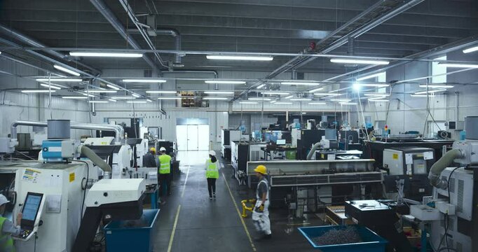 Establishing Footage with Professional Diverse Employees Working at an Industrial Production Plant. Specialists Producing Metal Components with Heavy Duty Tools and CNC Milling Machines